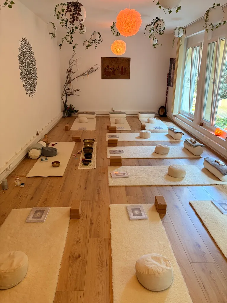 The studio prepared for a class: rows of white mats with cushions and bolsters in soft natural light
